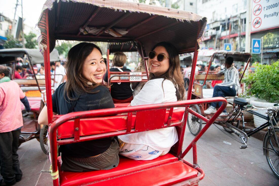 Two travellers smiling as they take a tide on a rickshaw in Delhi, India