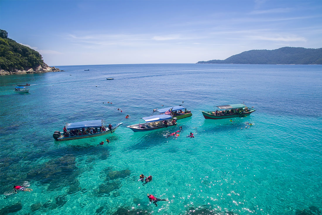 Travellers hop off boats to snorkel off Perhentian Island in Malaysia
