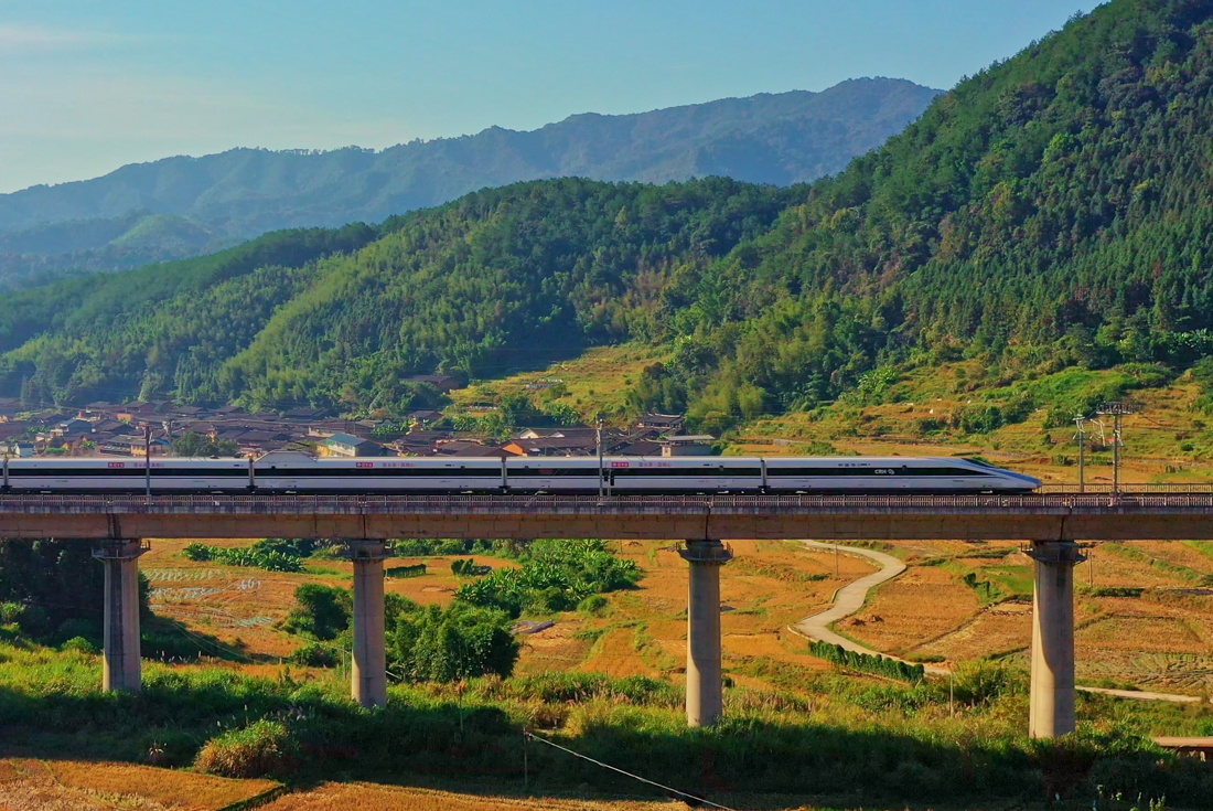 Bullet train on high rail line passing through the mountain backed agricultural landscape of Yunnan Province China