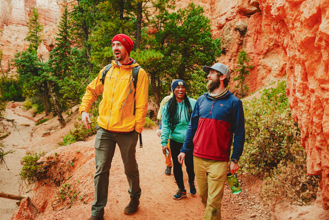 Intrepid travellers talk and laugh together among the bright orange stone and earth of Bryce Canyon's walls on a hike