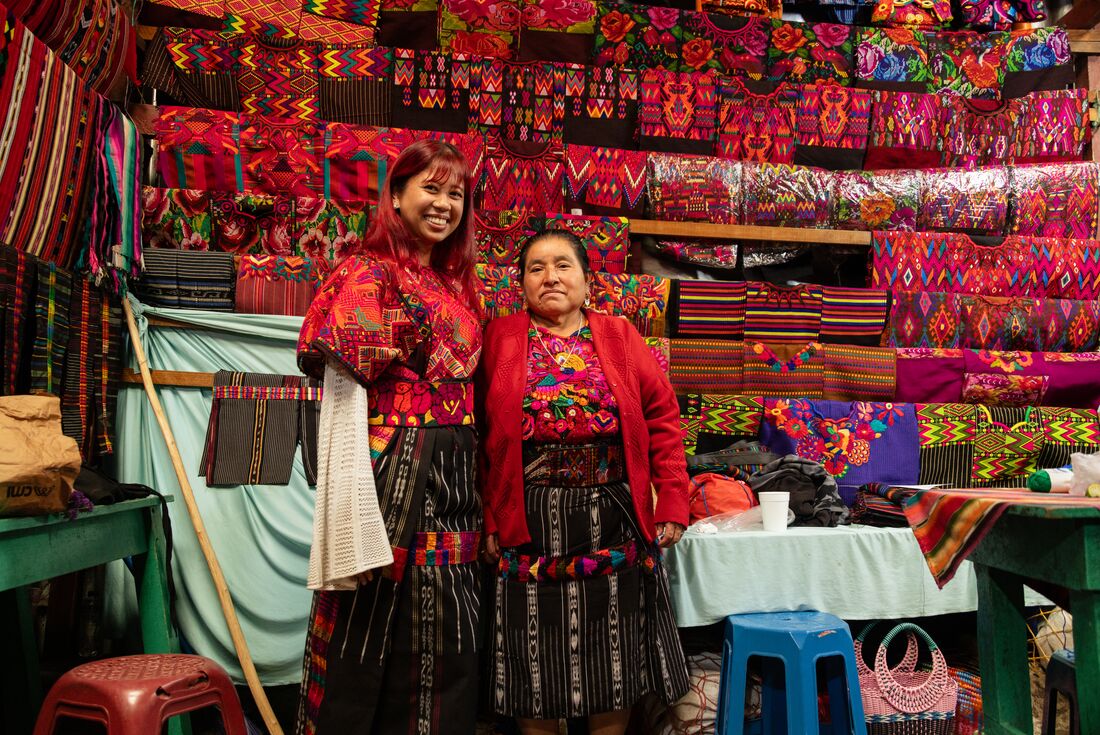 Intrepid traveller smiles happily with local textile merchant after a fitting in Chichicastenango markets