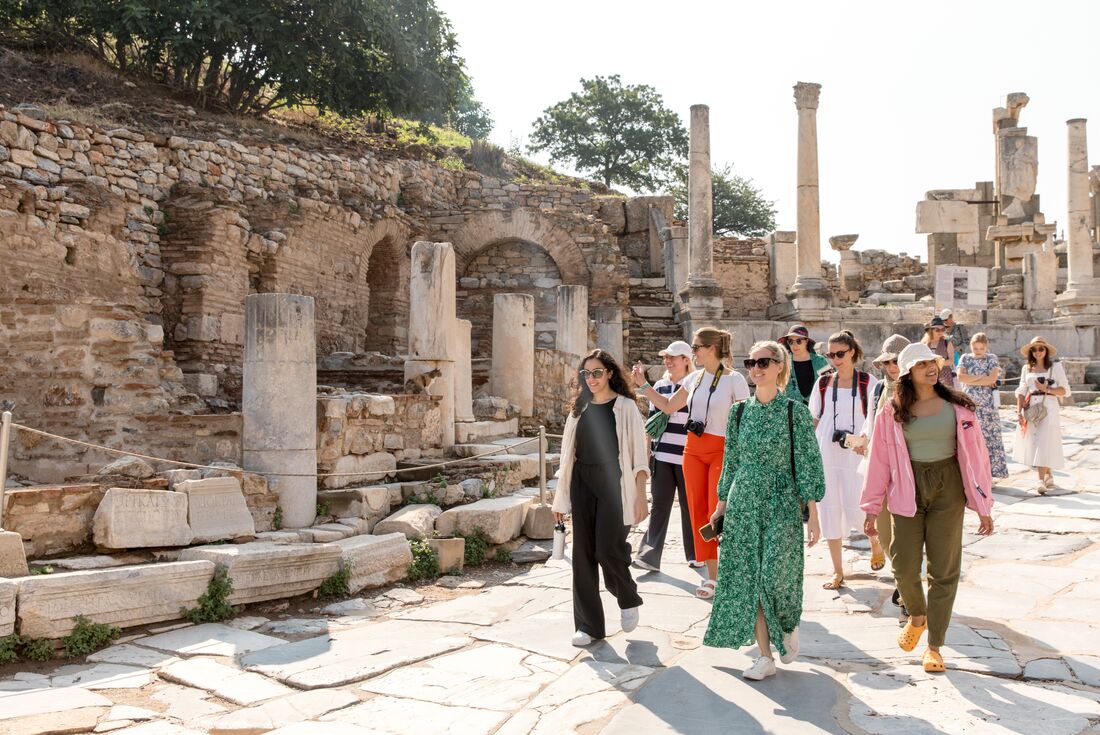 Womens expedition travellers walking on stone path through ruins of Ephesus