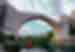 Intrepid traveller looks up from riverbed at the majesty of an ancient Ottoman bridge in Mostar Bosnia and Herzegovina