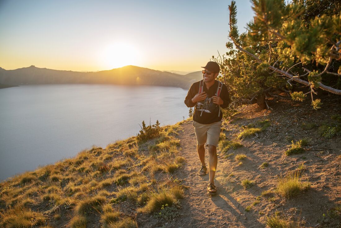 Traveller hikes around the rim of Crater Lake National Park in Oregon USA at sunrise