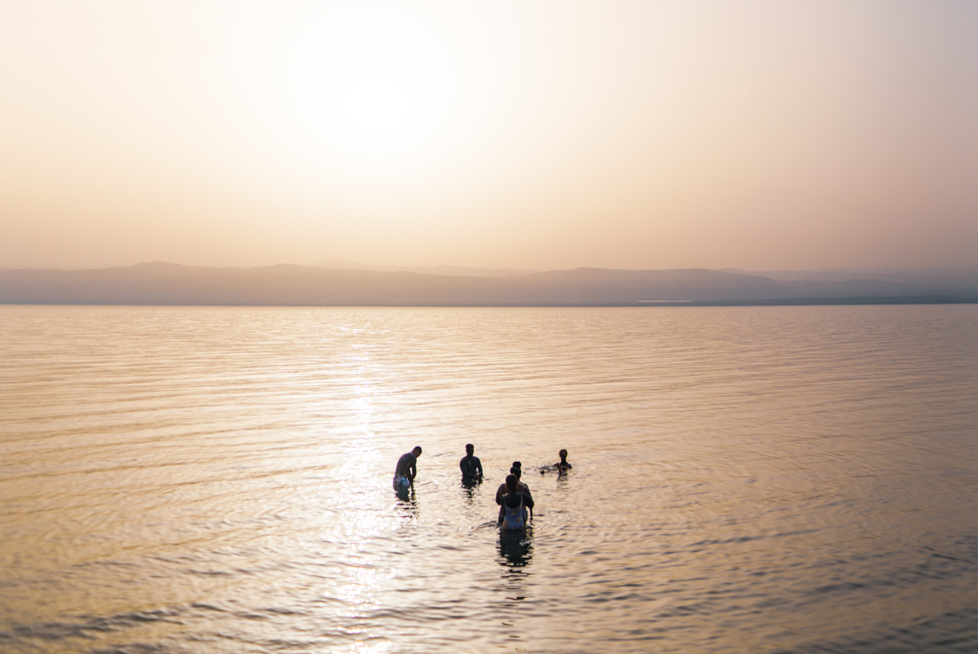 Group of travellers bathe in the salty Dead Sea in the haze of early morning