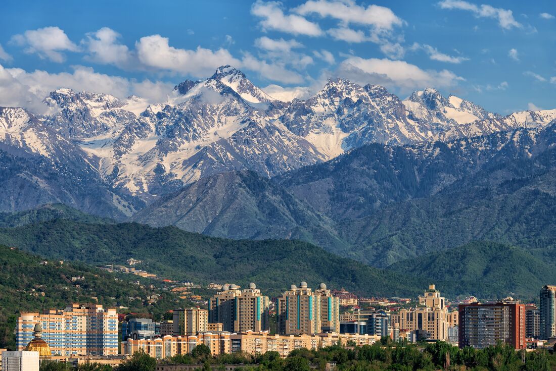 Alatau mountains rise high with snow caps behind Almaty buildings in Kazakhstan