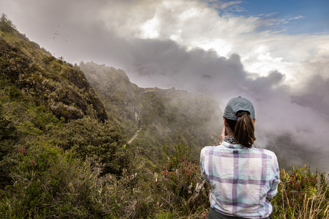 Intrepid traveller takes a photo of the misty mountain landscape at Sayacmarca archaeological site