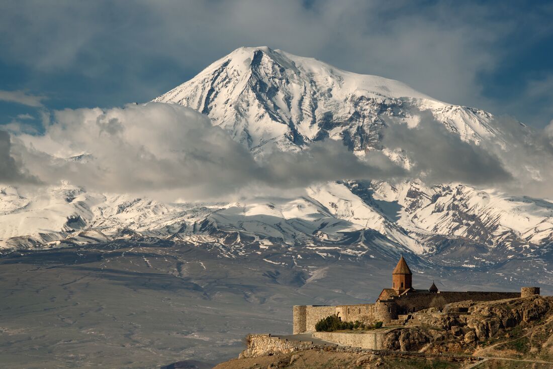 Wide view with Khor Virap Monastery buildings in foreground with Mount Ararat looming beyond