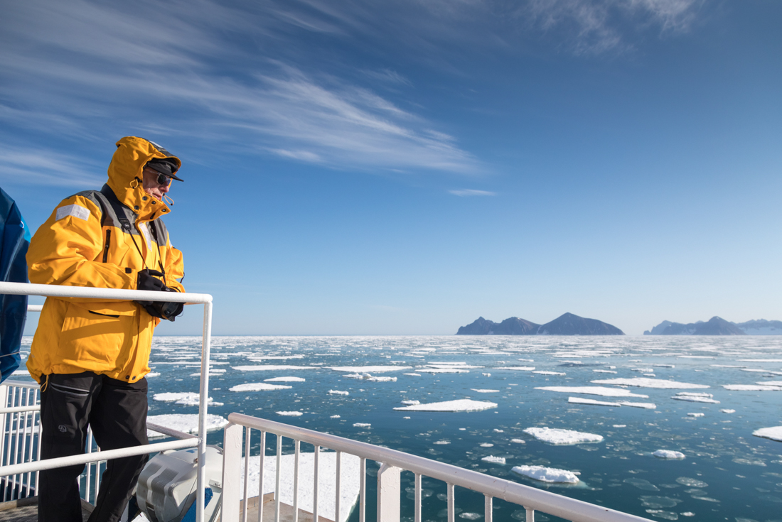 Traveller at a rail looking out over ice floes off Greenland's east coast