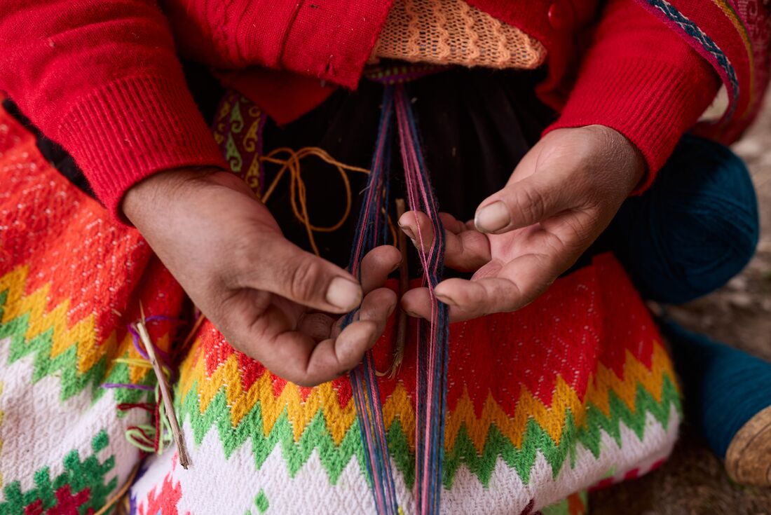 Closeup shot of Huilloc community member weaving in against bright coloured shirt in Peru
