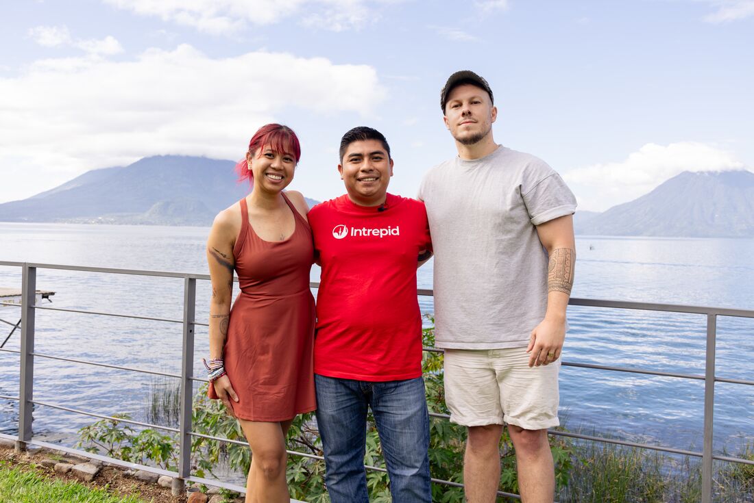 Leader and travellers taking a photo at Lake Atitlan with Volcano in the background, Guatemala