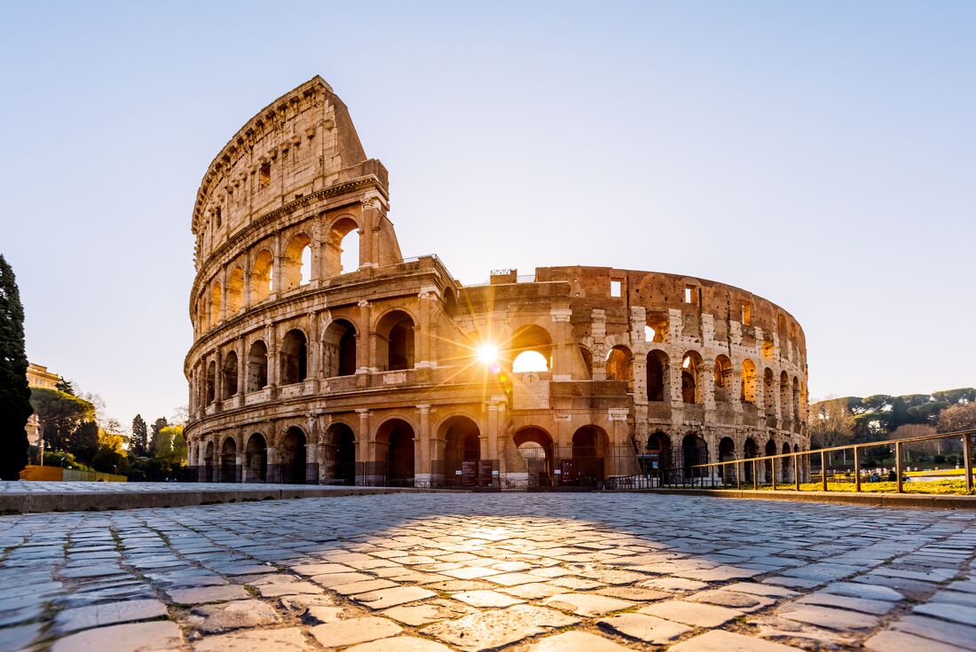 Sunrise beaming through an arch of the Colosseum