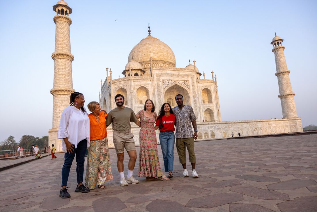 Travellers gather for a group shot in front of the Taj Mahal in the early morning light in Rajasthan