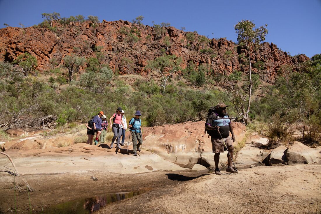 Leader Benji heads a group of Intrepid travellers crossing a small stream in Yapulpa (Glen Helen Gorge