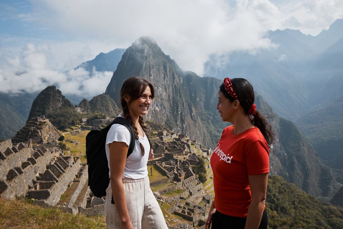 Traveller and leader stop and smile at the lookout of Machu Picchu