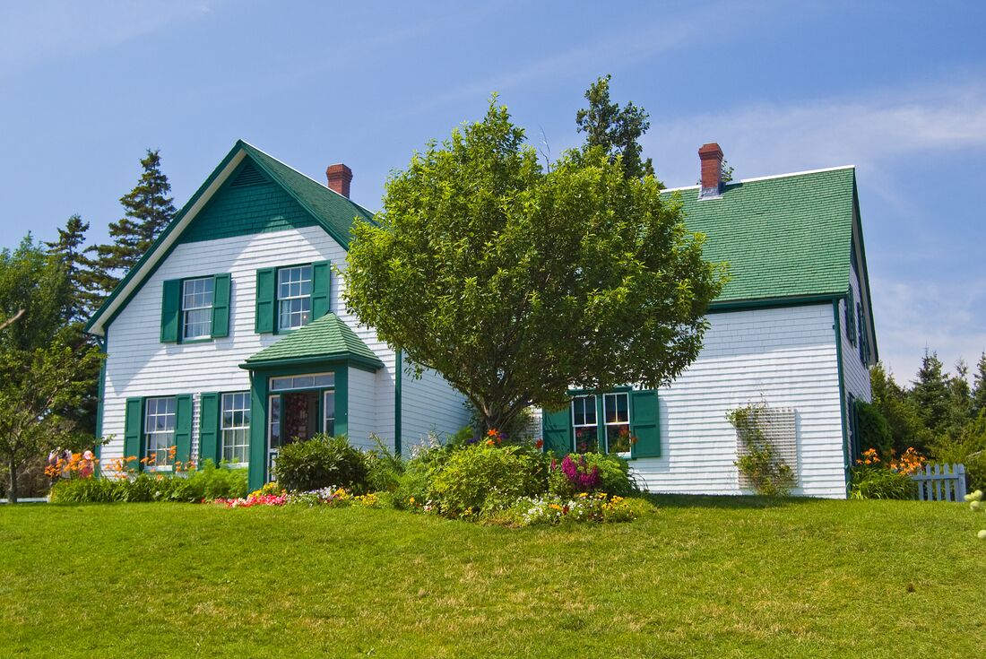 Green Gables Heritage Place, a classic white and green accented 19th century home, with a huge tree in the front yard