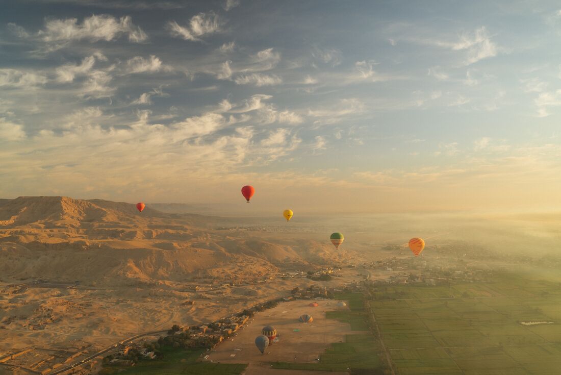 View from hot air balloon where multiple hot air balloons over Valley of the Kings in Luxor during sunrise, Egypt