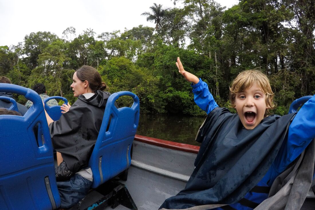 Happy son on family boat cruise in Amazon Rainforest, Ecuador