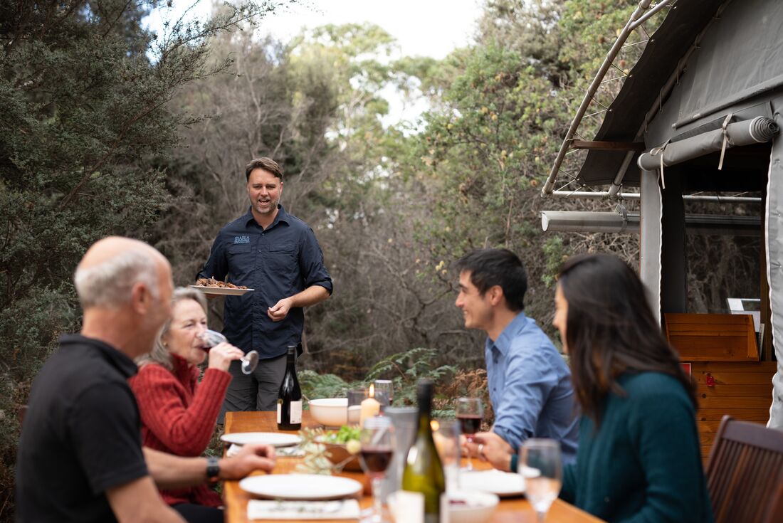 Lunch being served during outdoor group lunch, while travellers sip on wine, Maria Island, Australia