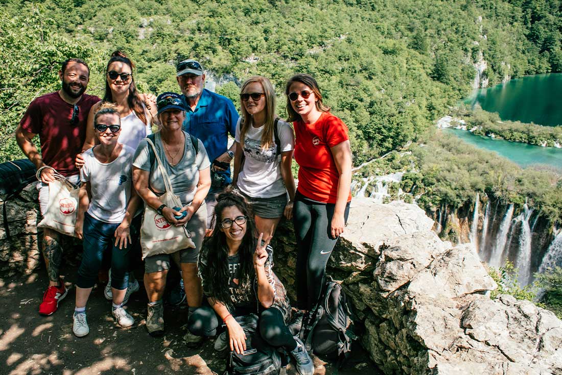 Travel group pose for photo with Plitvice lakes in the background