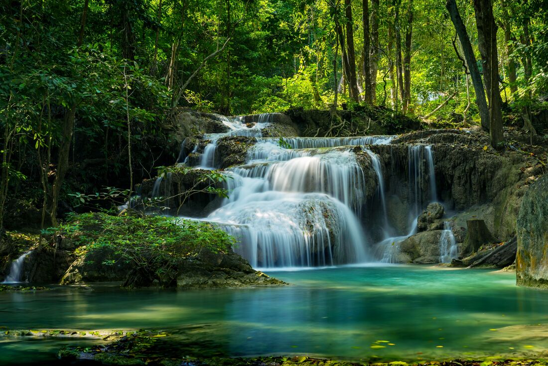 Lower waterfalls of Erawan National Park with deep forest surrounding them in northern Thailand