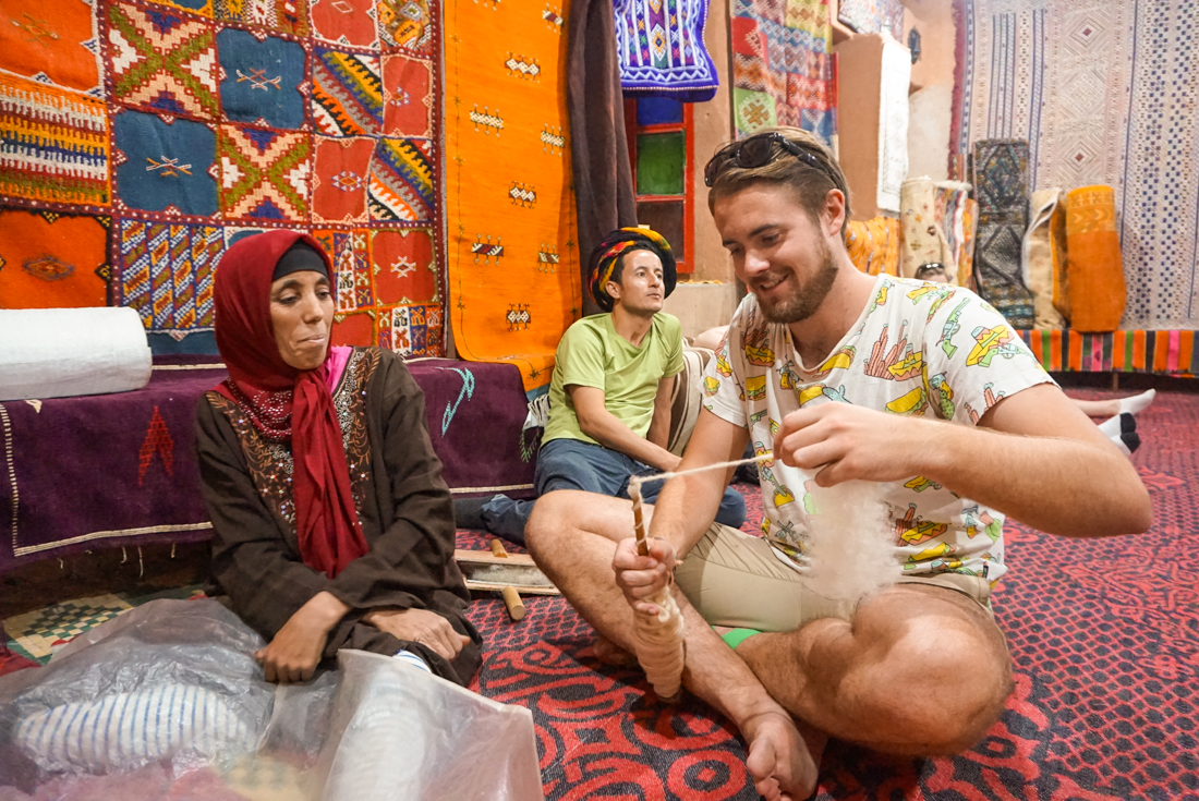 Traveller examines some raw fabric on a spool with locals in Fes Bazaar in Morocco