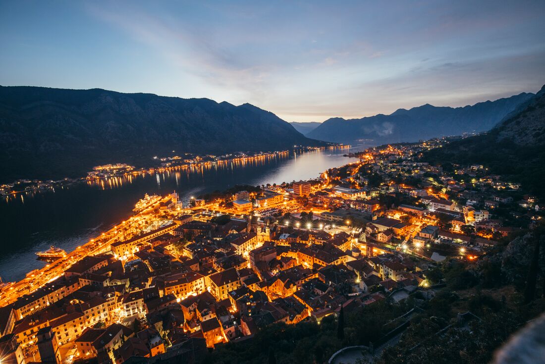 Aerial shot of Bay of Kotor in Montenegro at night time, with the town lights glowing 