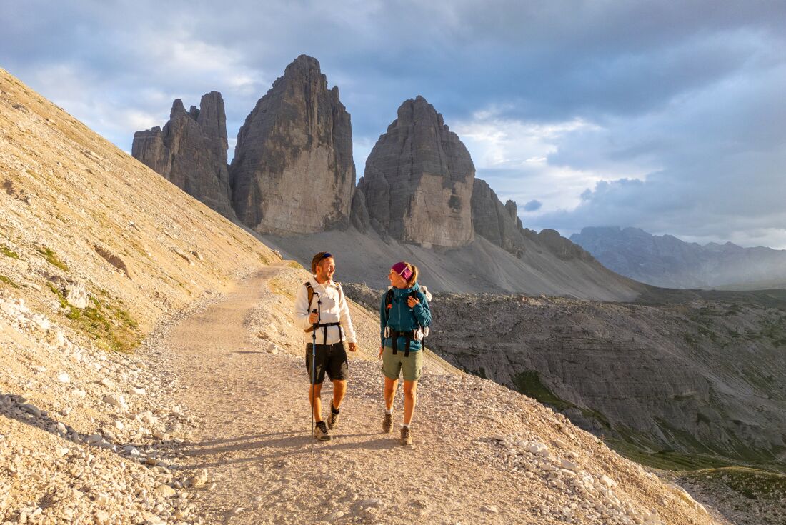 Intrepid travellers talk and smile while hiking Tre Cime di Lavaredo in the Italian Dolomites