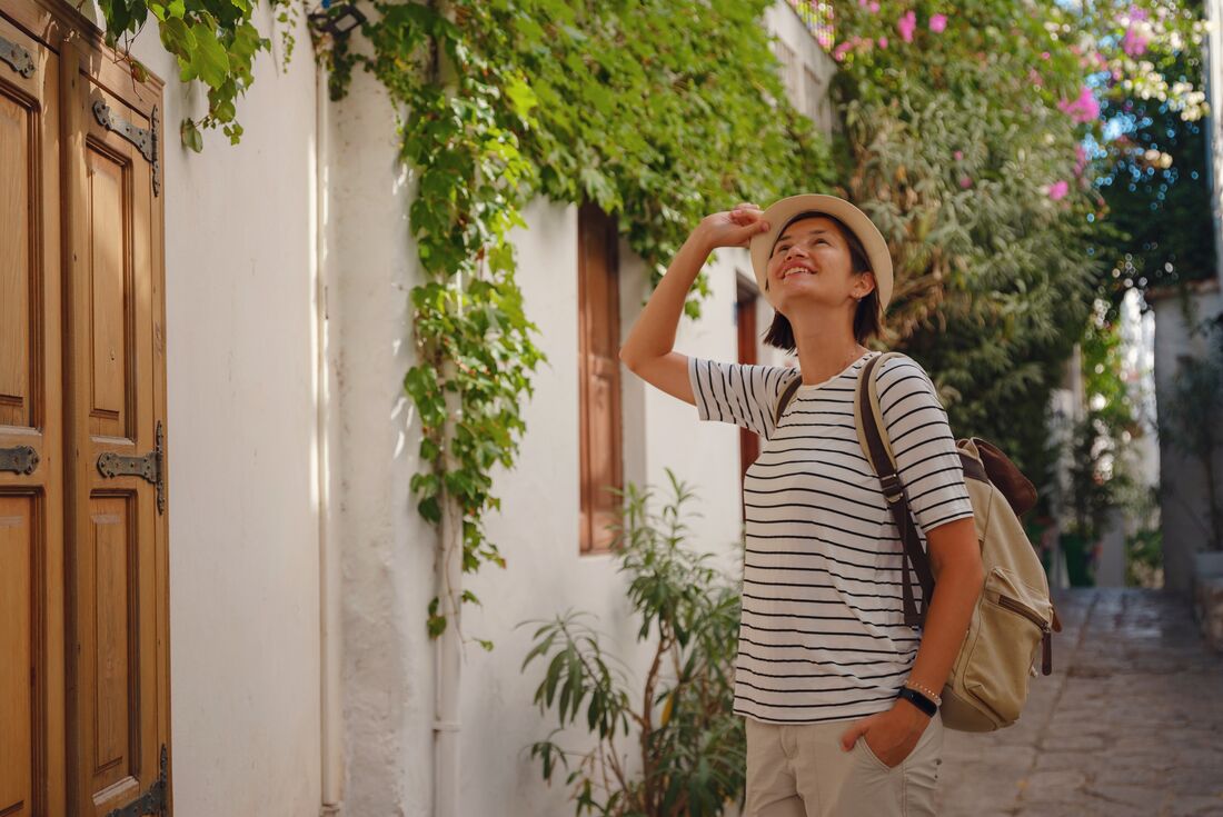 Traveller in the streets of Marmaris looks up at old buildings covered in ivy vines in Turkish riviera